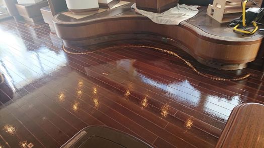Suelo de madera barnizado con acabado brillante en el interior de un barco, tras trabajos de acuchillado y barnizado profesional