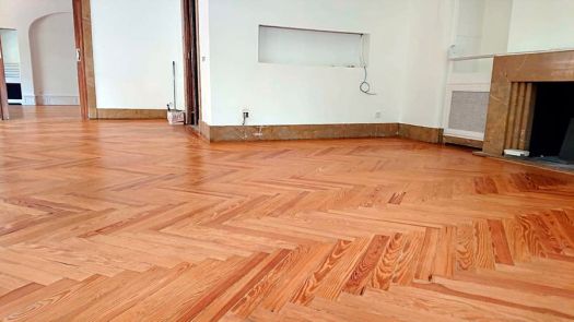 Parquet de madera en espiga recién restaurado y barnizado, salón amplio con chimenea de mármol y paredes blancas